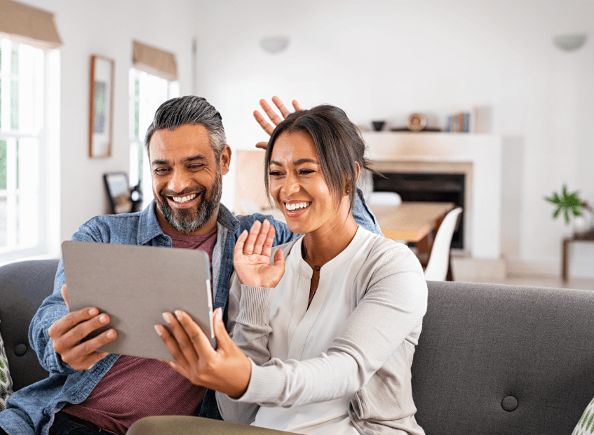Smiling couple using a tablet together, representing the supportive and convenient experience of becoming a patient through telepsychiatry and therapy